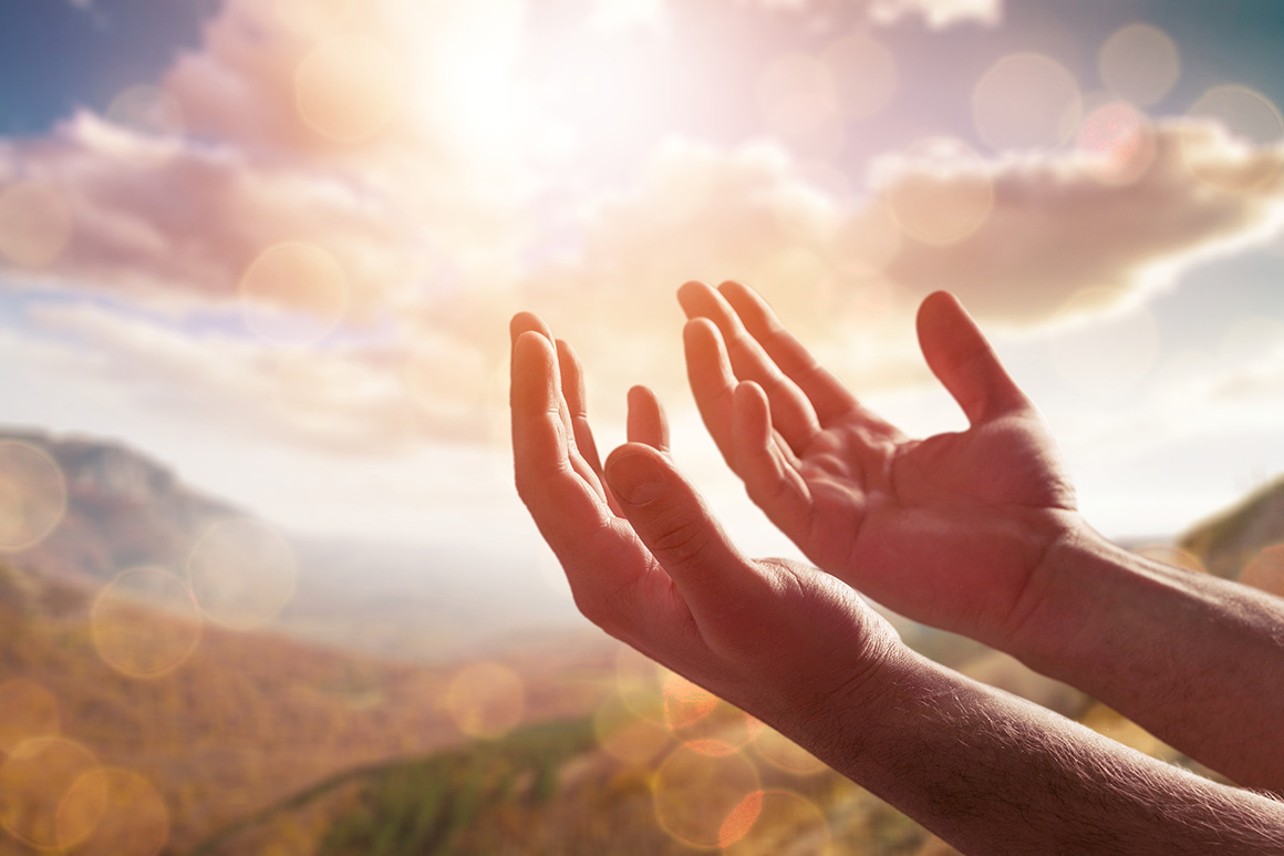 Hände zum Himmel hin gerichtet, dem Licht entgegen, das aus den Wolken kommt.